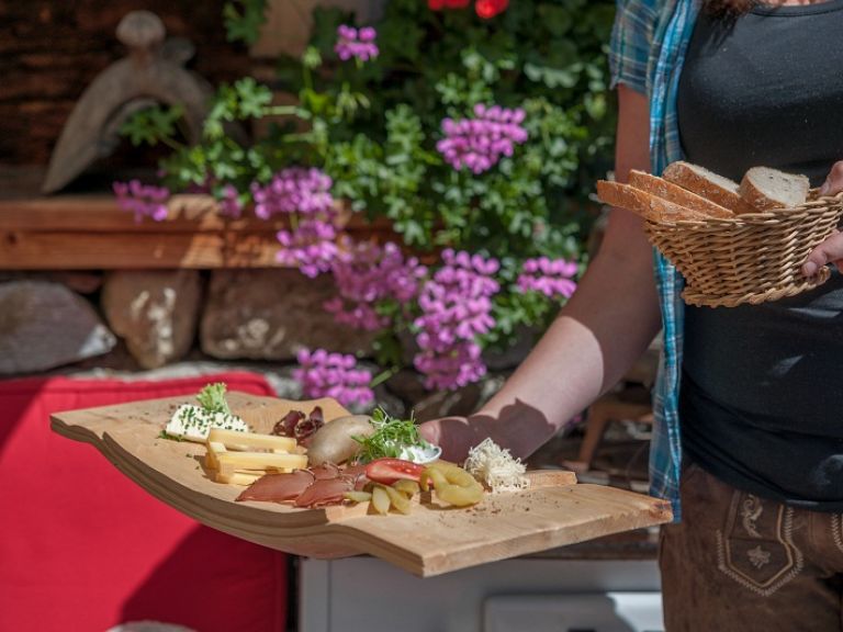 A woman, holding a plate with cheese and bacon.